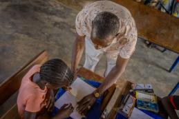 A teacher showing a student how to use the supplies included in the school kit she received. Mali.