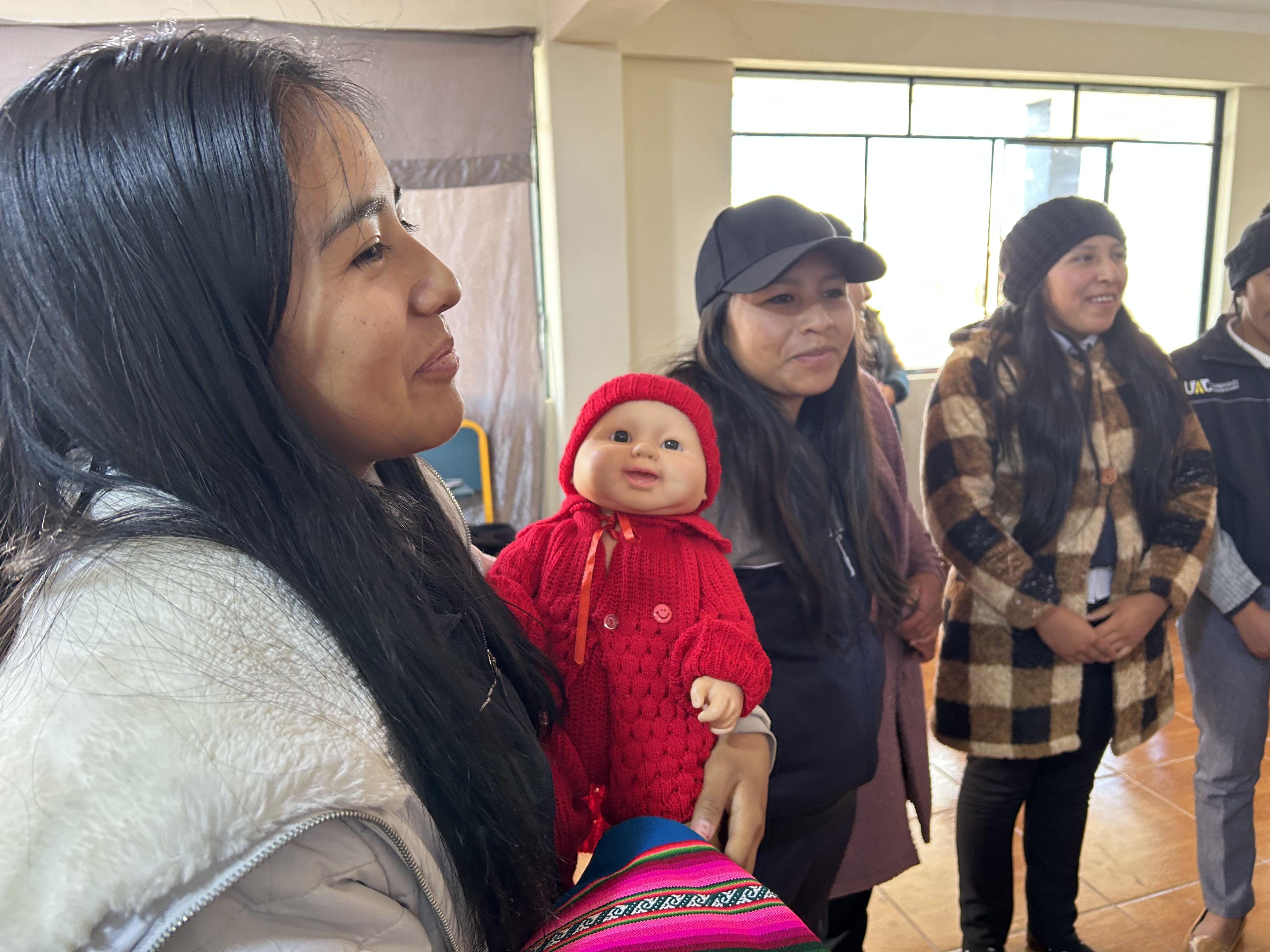 Young girls, one holding a doll. In classroom
